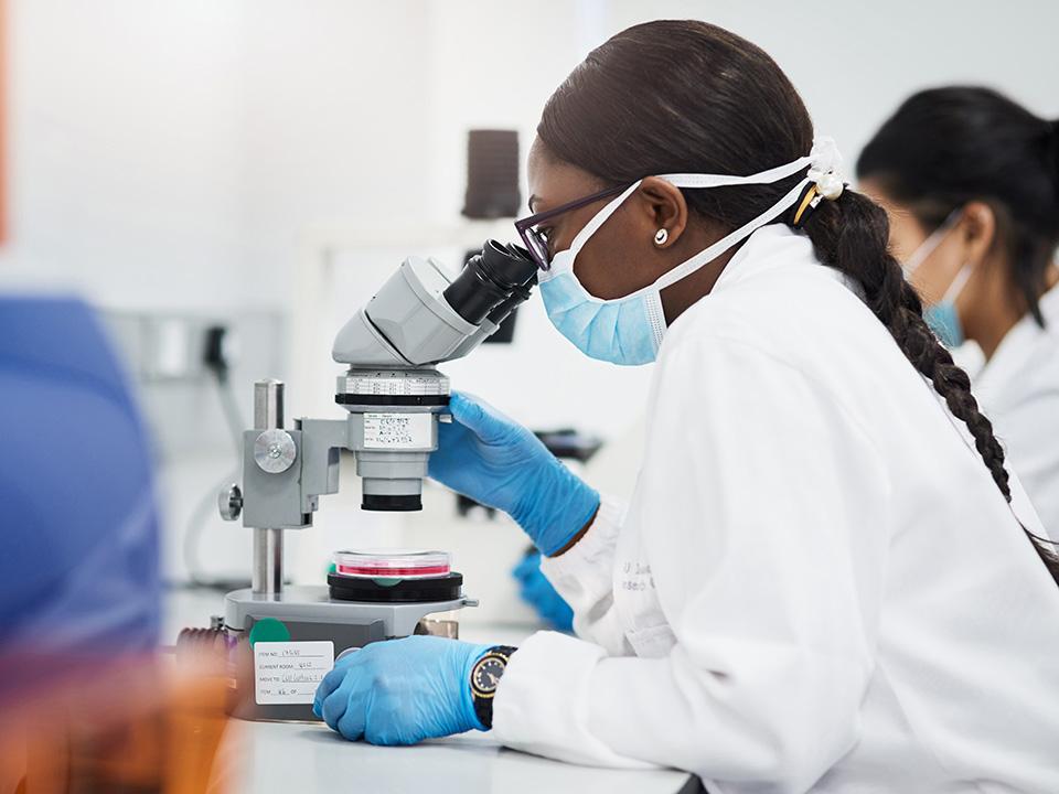 Woman in a lab looks into a microscope